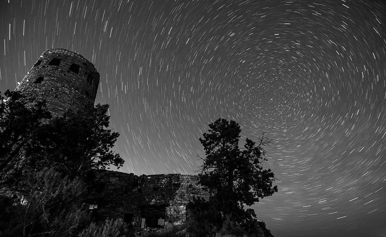Circular star trails above Desert View Watchtower and trees at Grand Canyon’s South Rim.