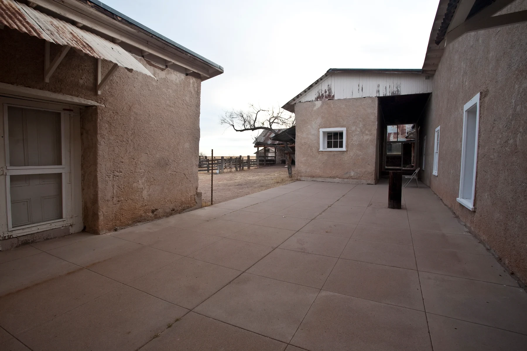 Adobe walls, doors and a covered passage at Empire Ranch, with a corral visible beyond.
