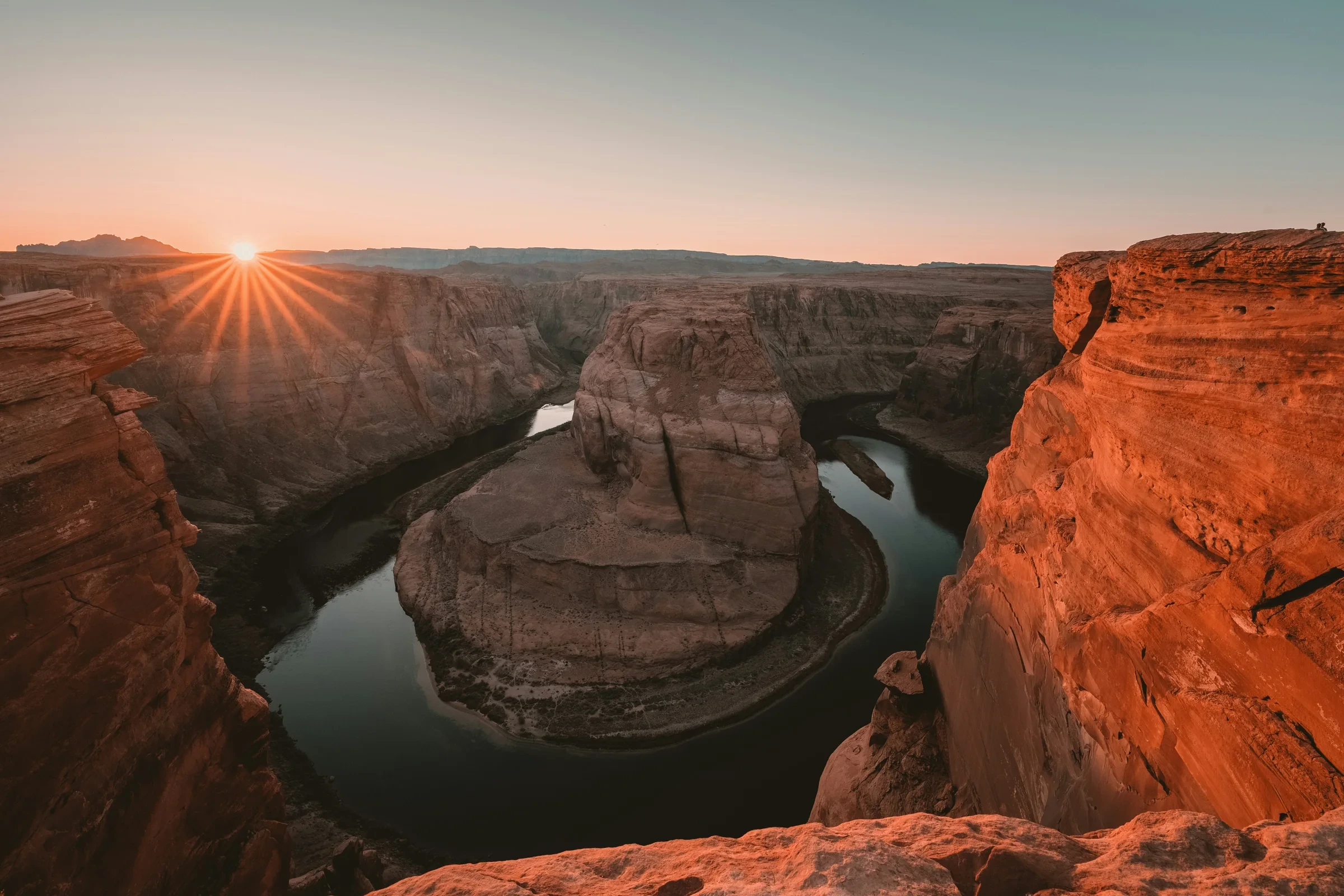 Colorado River curving around a sandstone butte beneath a low sun at Horseshoe Bend.