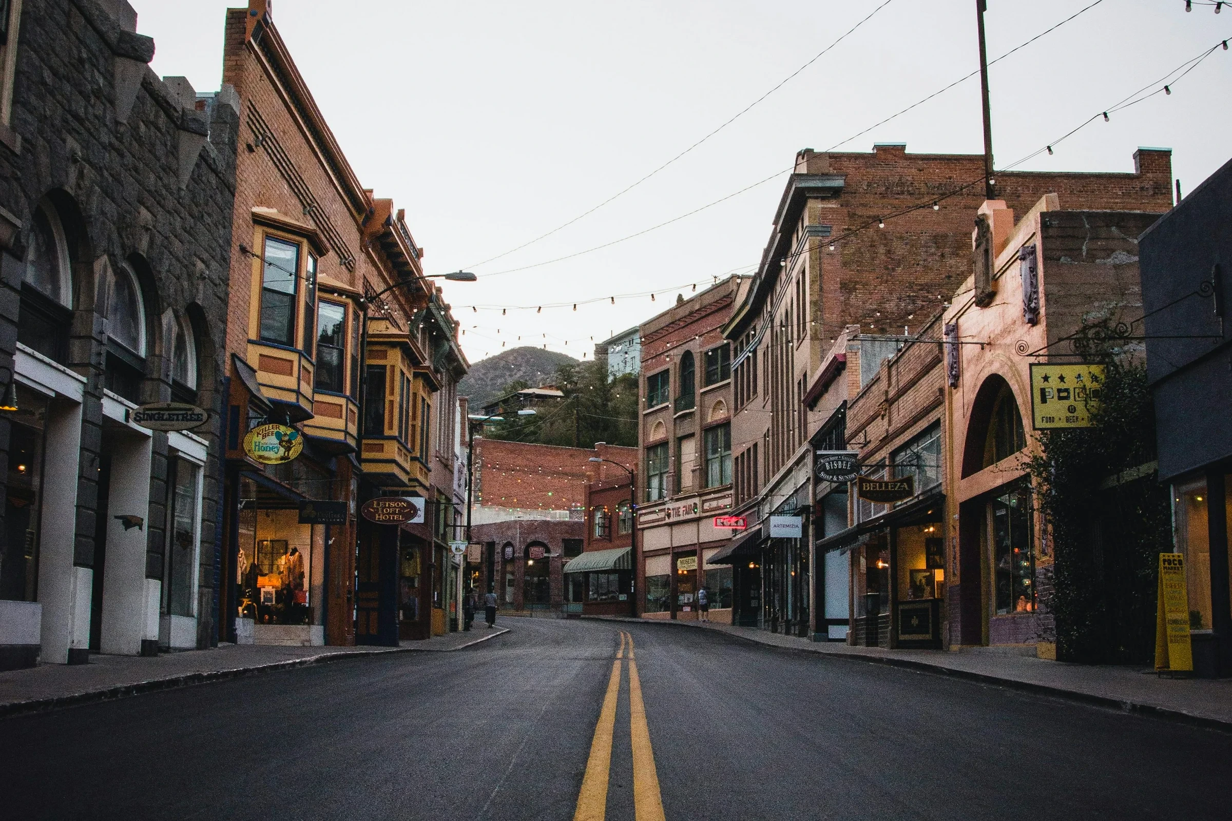 Brick storefronts lining a curving street beneath string lights in Bisbee, Arizona.