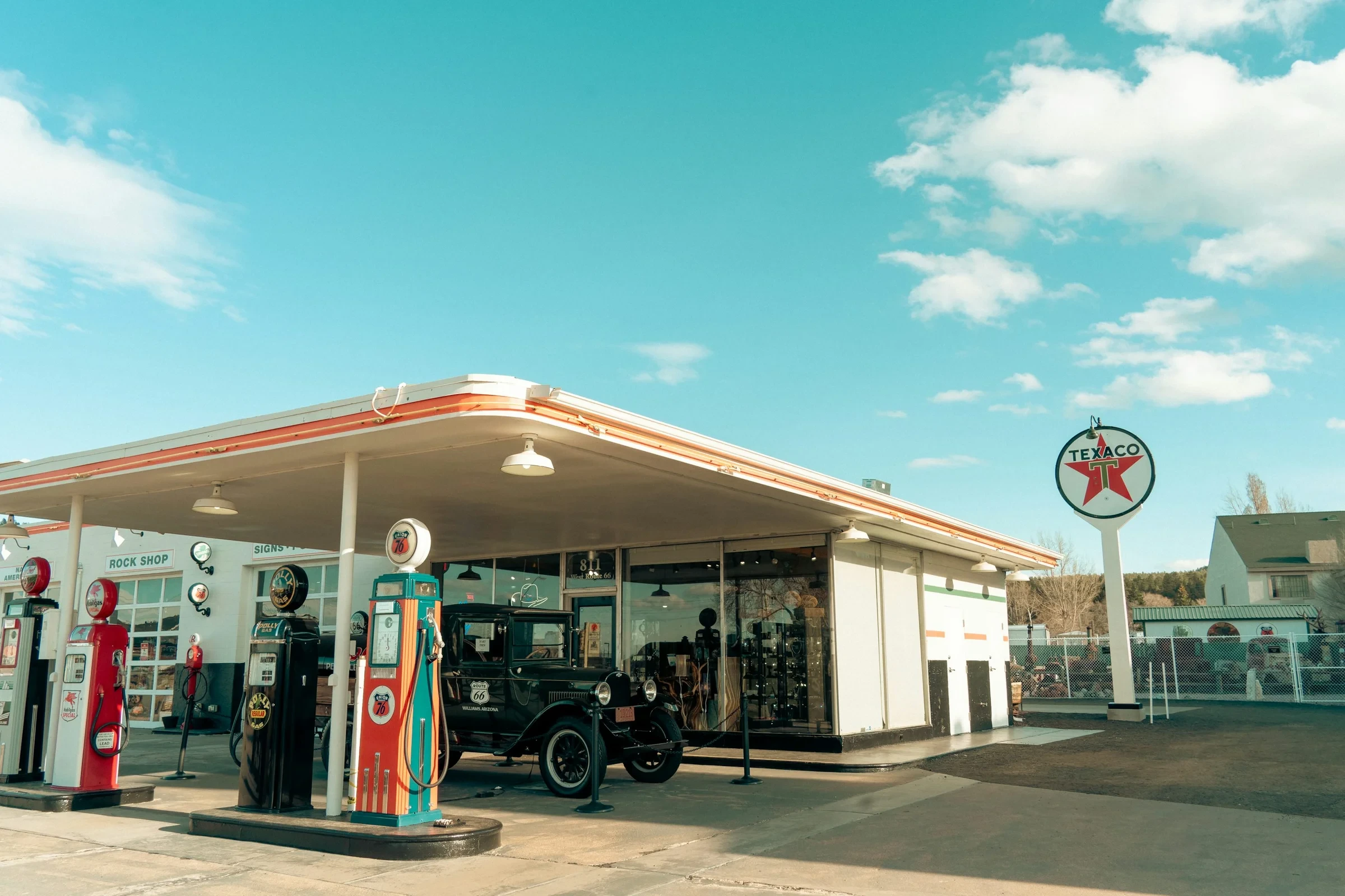 Vintage fuel pumps and an old car outside a Route 66 storefront in Williams, Arizona.