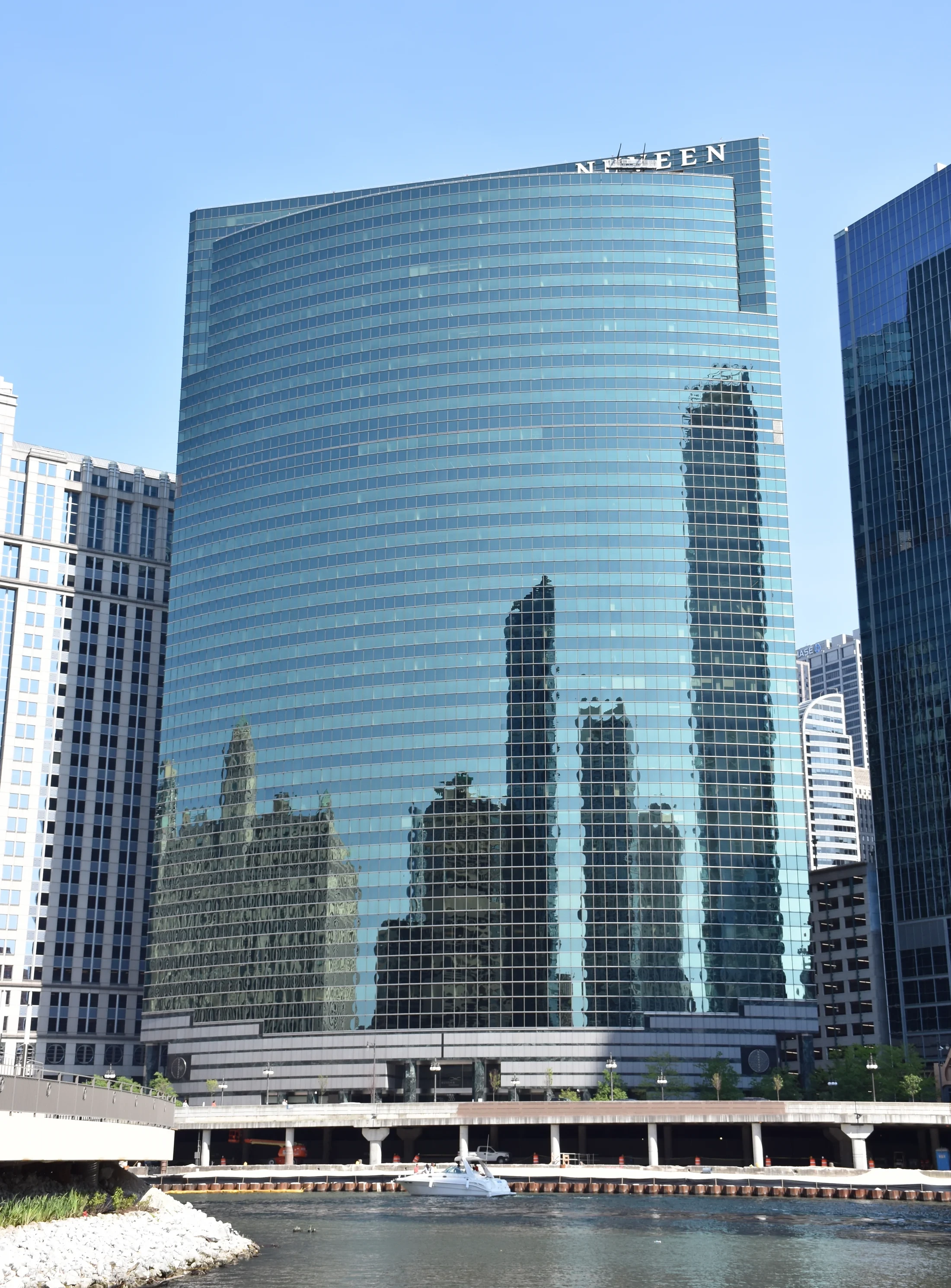 The curved glass facade of 333 West Wacker reflects neighboring buildings above the river.