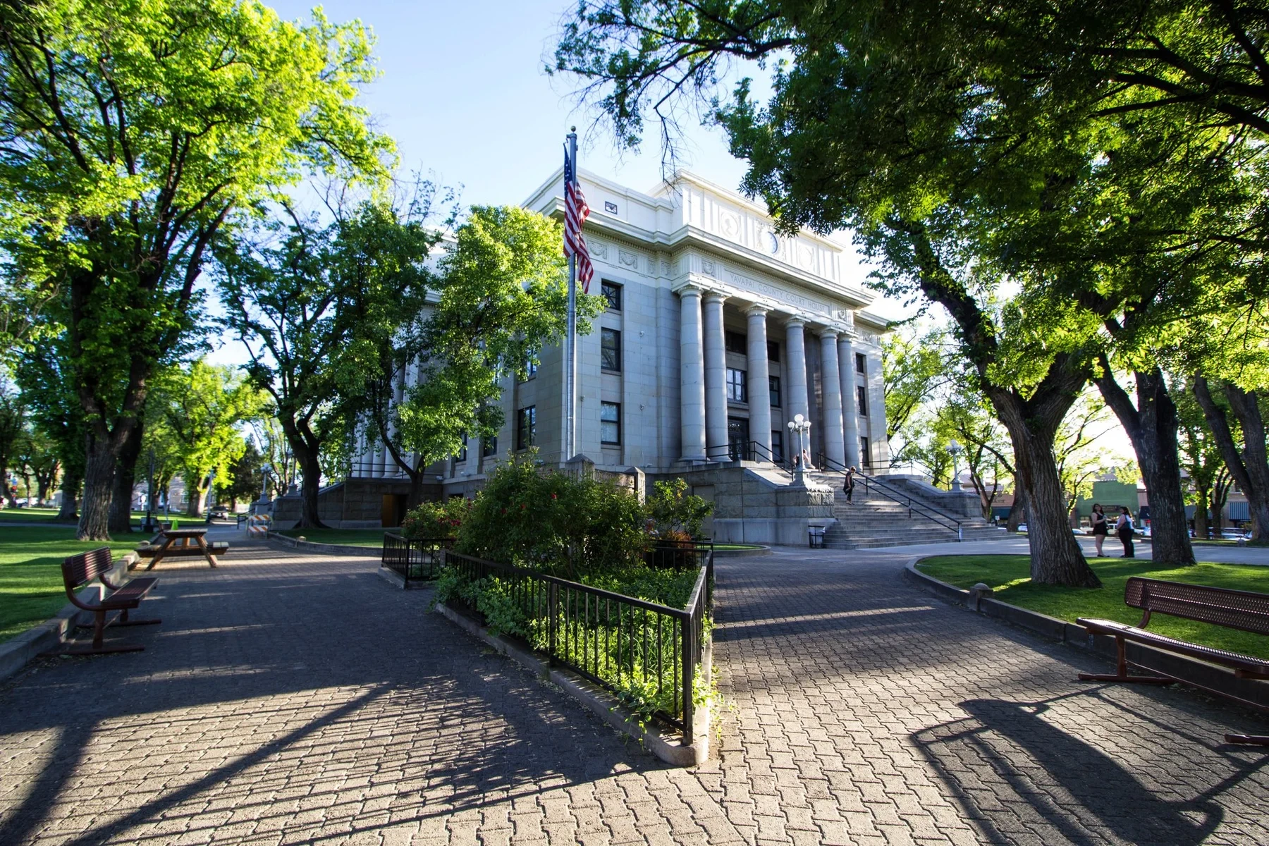 The columned Yavapai County Courthouse framed by leafy trees and brick paths.