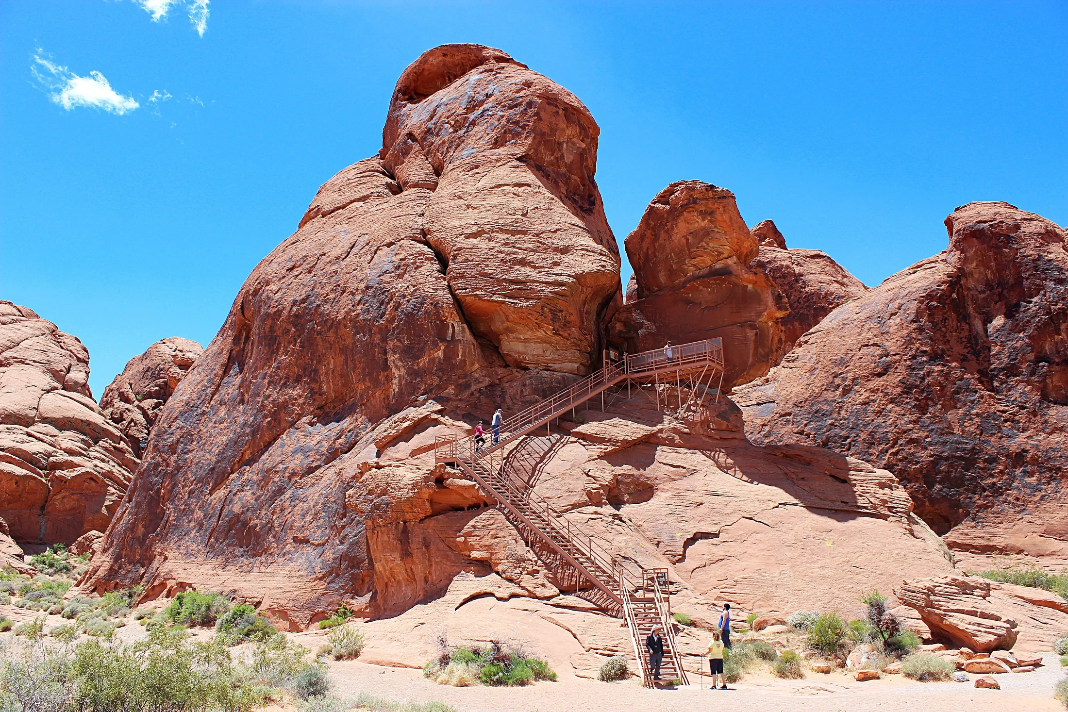 A metal staircase climbs beside red sandstone to the viewing platform at Atlatl Rock.