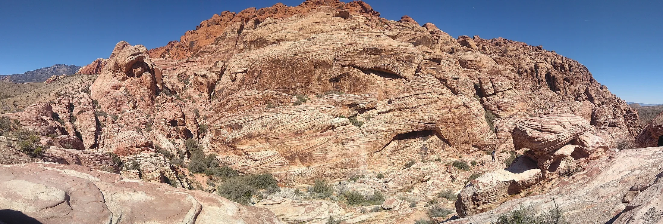 Layered cream and red sandstone rising beside a rocky path at Red Rock Canyon.