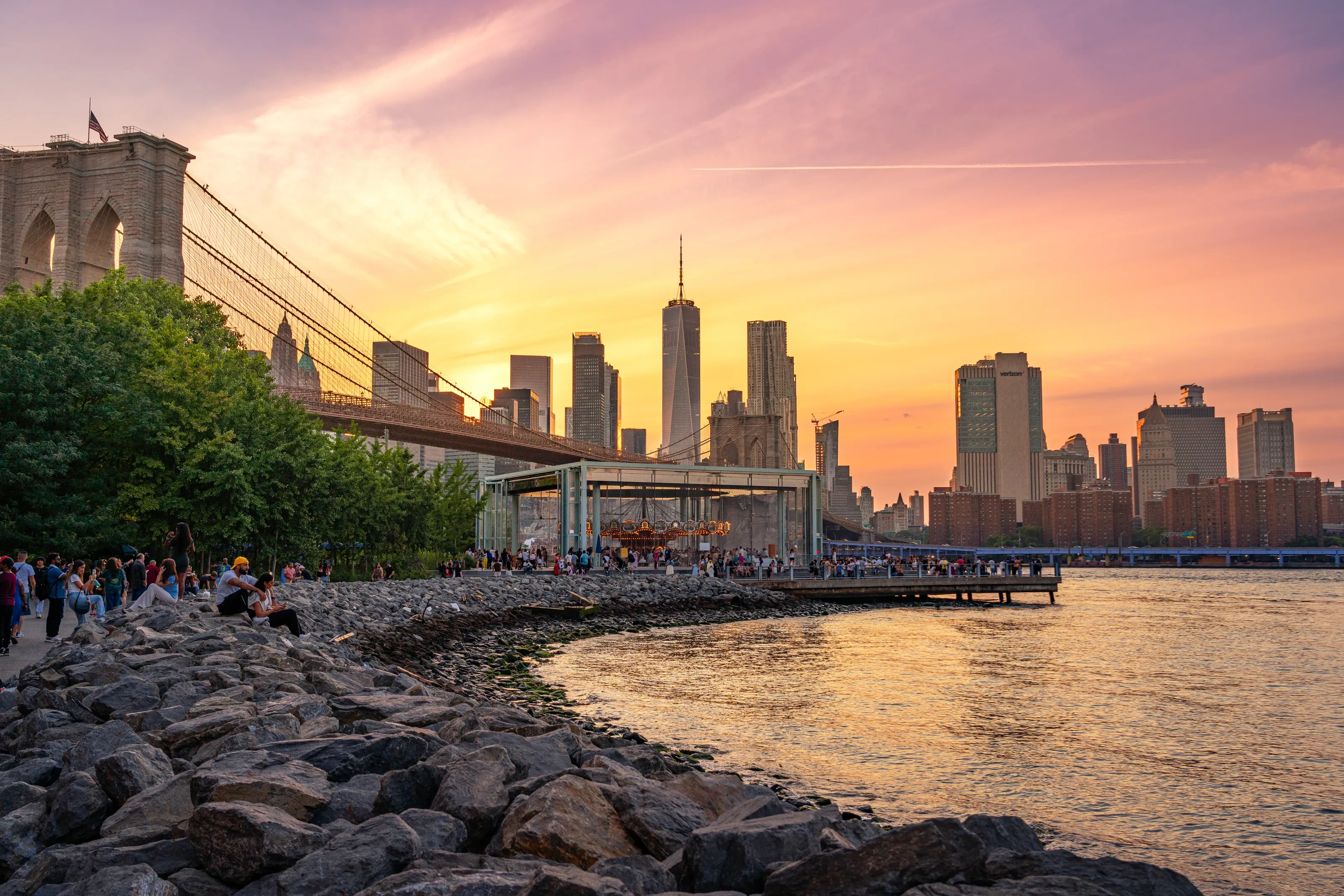 Brooklyn Bridge, Jane's Carousel, and the Manhattan waterfront beneath a colorful sunset